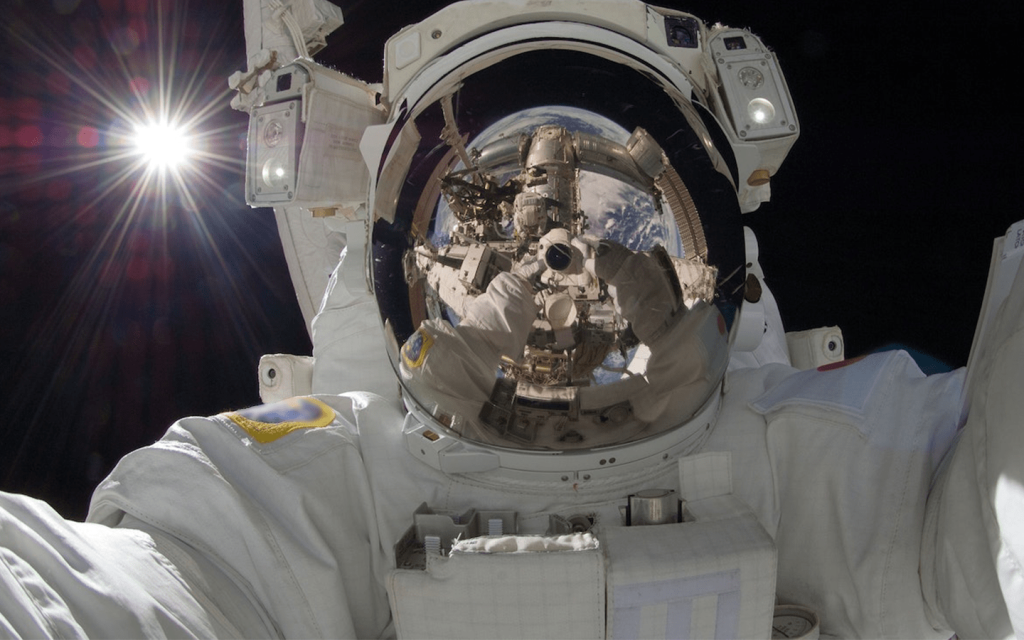 This is a suited astronaut in space with the sun behind them. The astronaut's helmet shows a full but minature image of the astronaut, representing the them of "Ad Astra".