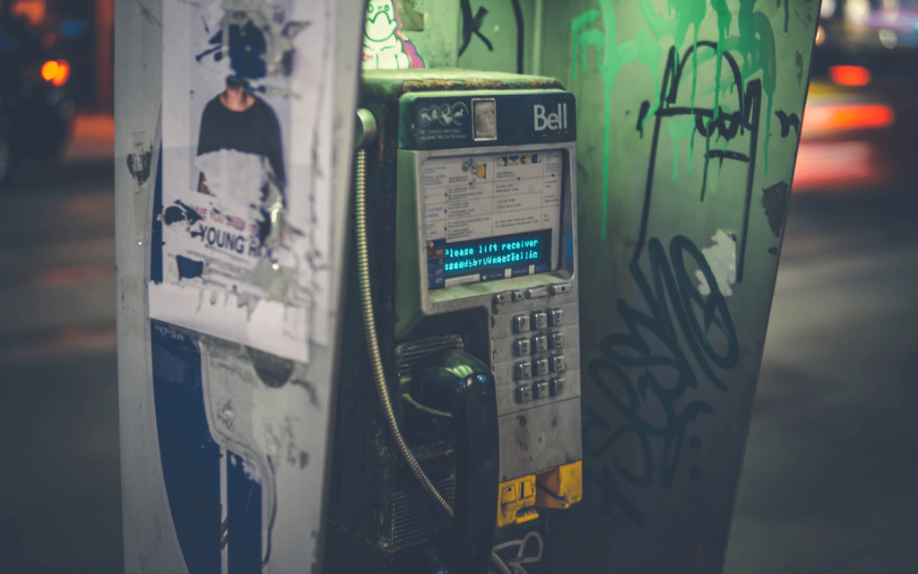 This is a pay phone with grafitti and ripped poster at night. This represents the central action scene in "The Guilty".