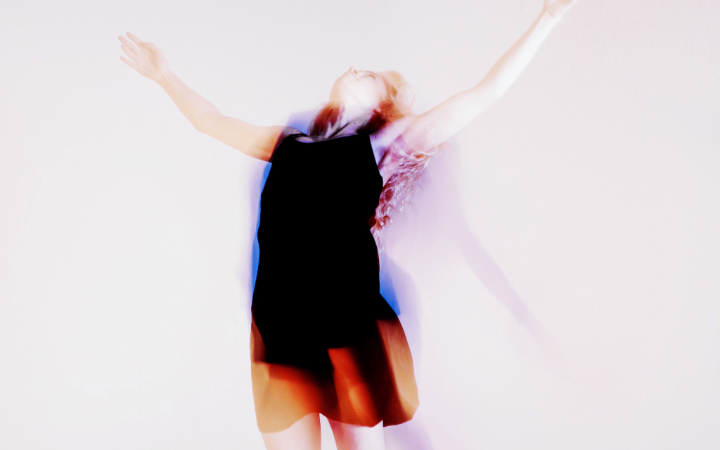 This is a woman with raised arms and head tipped towards the sky with pink-ish, violet, blue-ish hue. A faded show of a body appears behind her. There is a diluated, washed effect of the image and the shadow such that it looks like the woman is been evangelized. It is used to illustrate Lyn's awakening into religion in episode 3, season 4 of Vida.