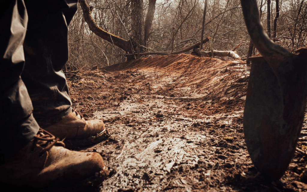 This is a man in dark brown slacks and boots in the muddy woods during the bright summer afternoon. The man is standing just a step away from a shovel which is helf vertifically, suggesting that he is holding the shovel. It is used to describe the fact that the murder in Beyond Evil is mysterous and dangerous. In episode nine, we discover that a body has been burried, so the image is also used to illustrate this  gruesome information.